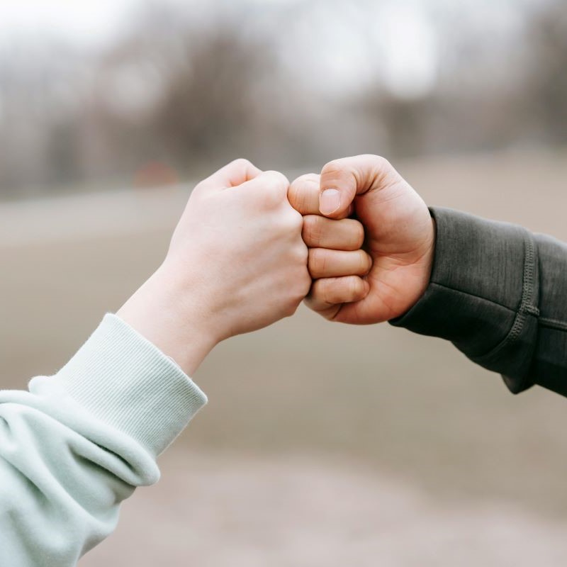 Zwei Personen führen einen Handschlag über einem Geschäftsplan aus